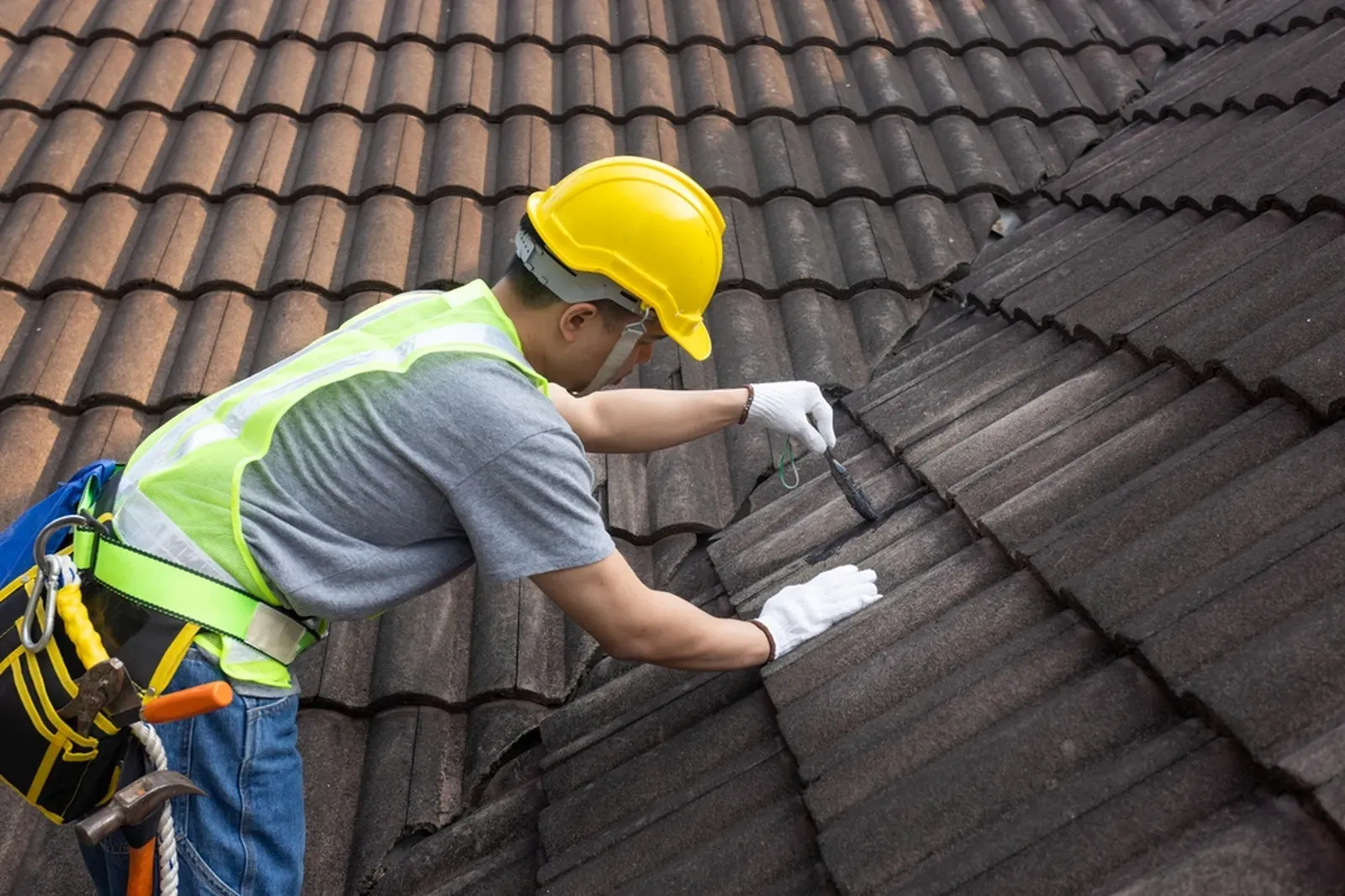 A residential roof with tile shingles being repaired, approved by a hero. | You First Home Services