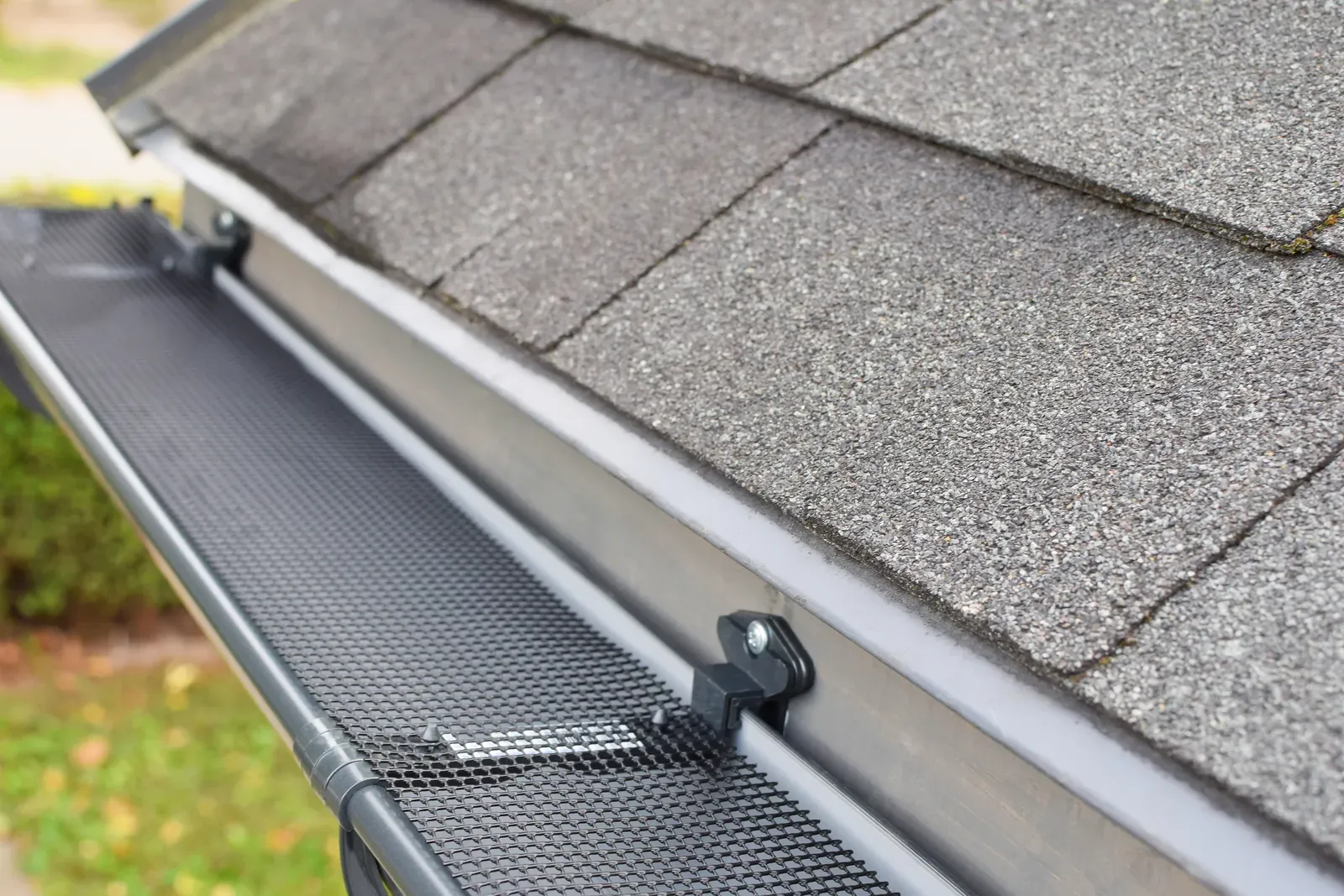 A new gutter being installed on a residential building with gutter guards. | You First Home Services