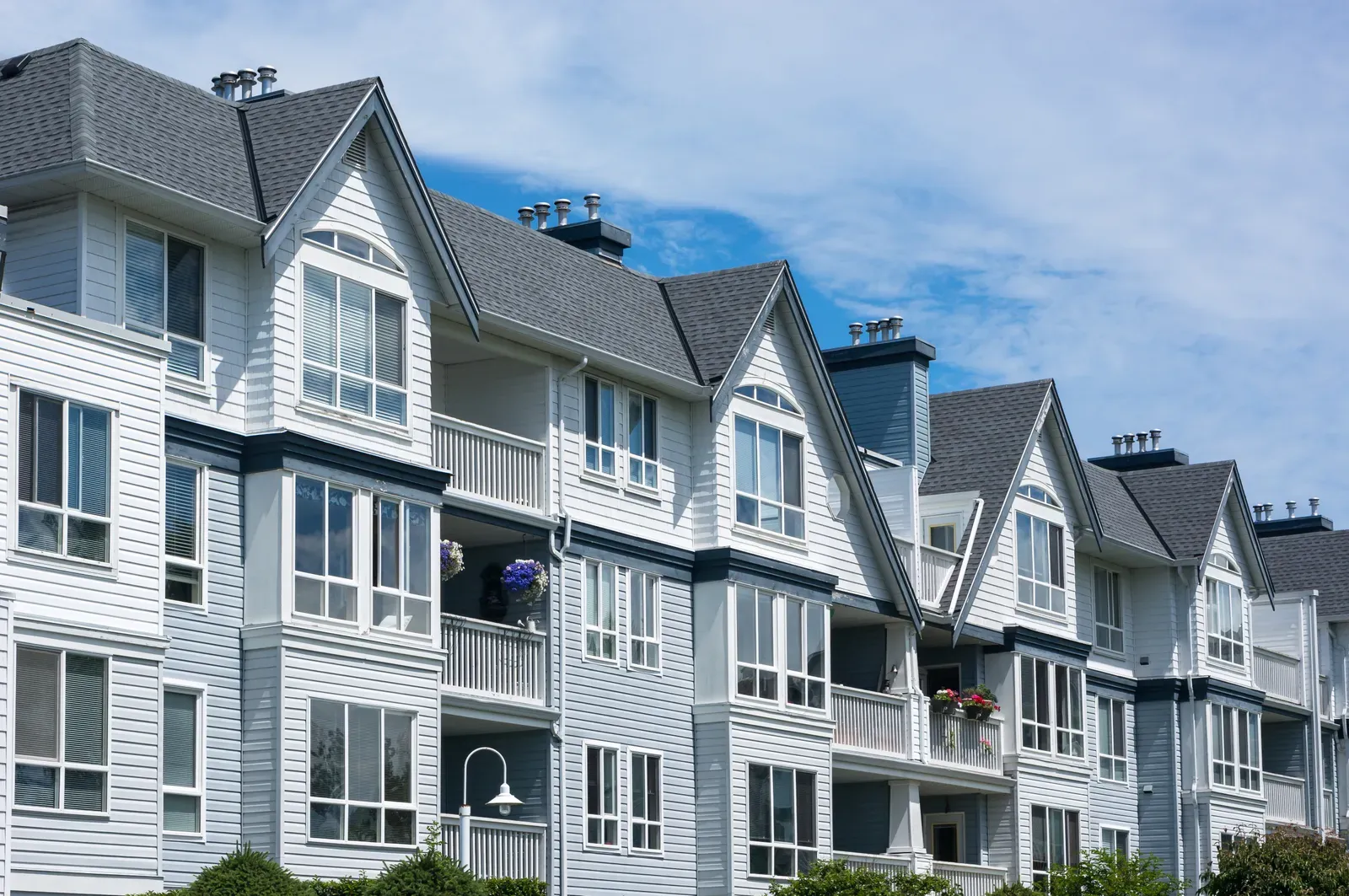 A photo of a multifamily building with newly installed asphalt roof and vinyl siding, both hero-approved and ready for replacement or installation. | You First Home Services