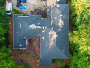 A close-up photo of an asphalt shingle roof on a residential building with a sign indicating it is being replaced. | You First Home Services